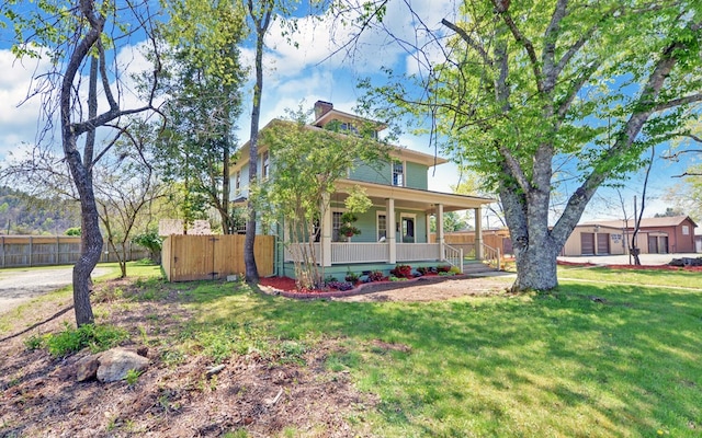 american foursquare style home with a front yard, fence, and covered porch