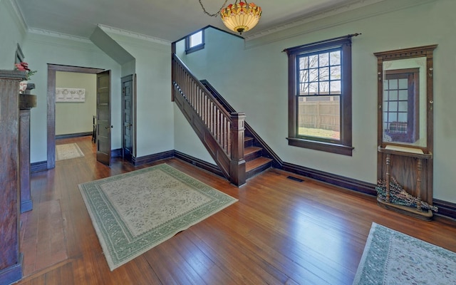 foyer featuring visible vents, baseboards, ornamental molding, stairs, and hardwood / wood-style floors