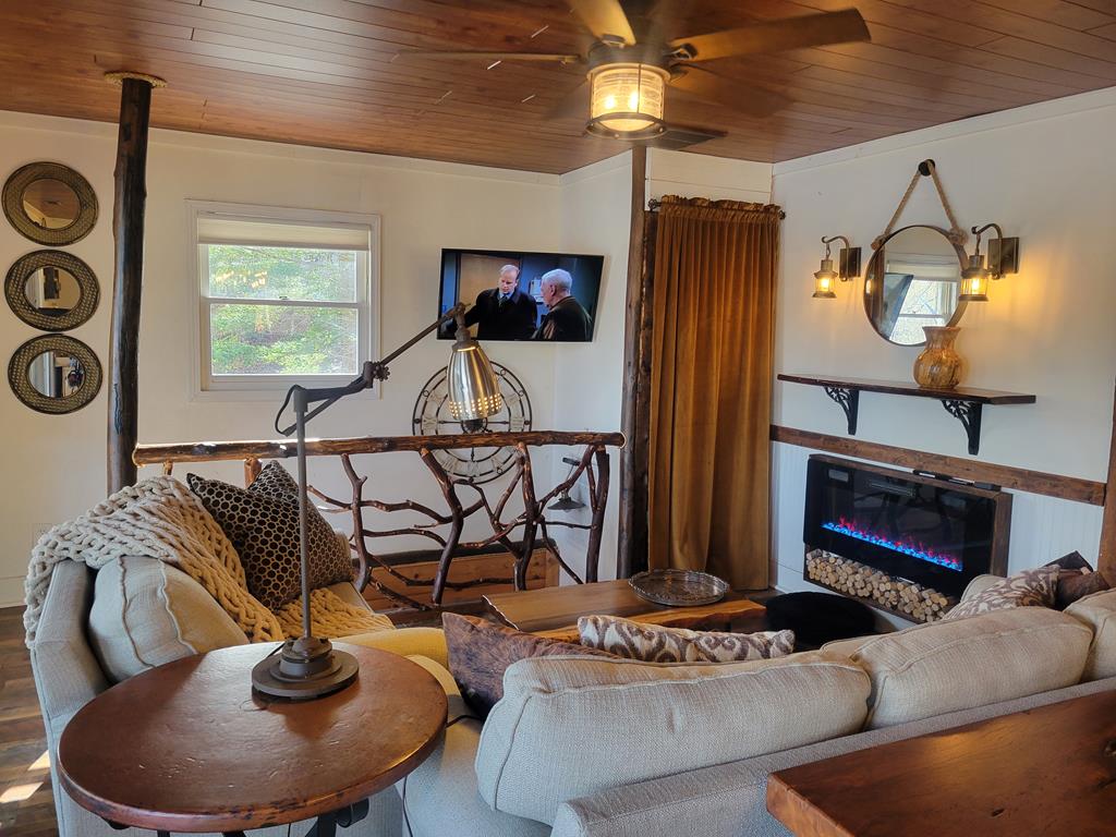 living area featuring wood finished floors, wood ceiling, and a glass covered fireplace