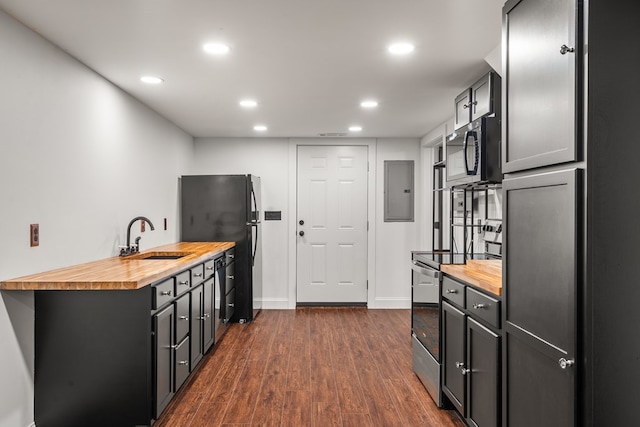 kitchen featuring electric panel, dark wood-style flooring, a sink, butcher block counters, and stainless steel appliances
