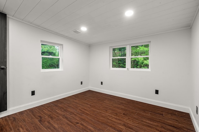 spare room featuring crown molding, dark wood-style flooring, and baseboards