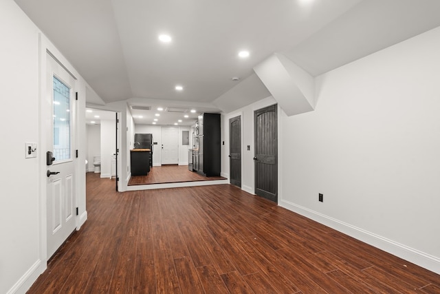 unfurnished living room featuring recessed lighting, baseboards, vaulted ceiling, and dark wood finished floors