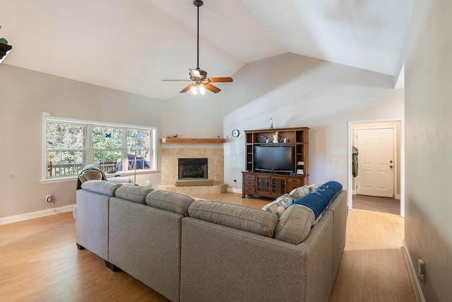 living room with a fireplace, light hardwood / wood-style floors, high vaulted ceiling, and ceiling fan