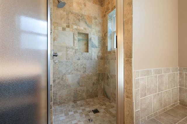 bathroom with a tile shower and tile walls