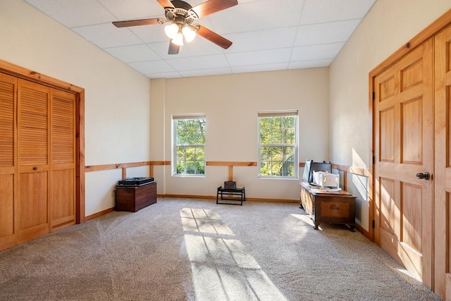 interior space featuring a paneled ceiling, light colored carpet, and ceiling fan