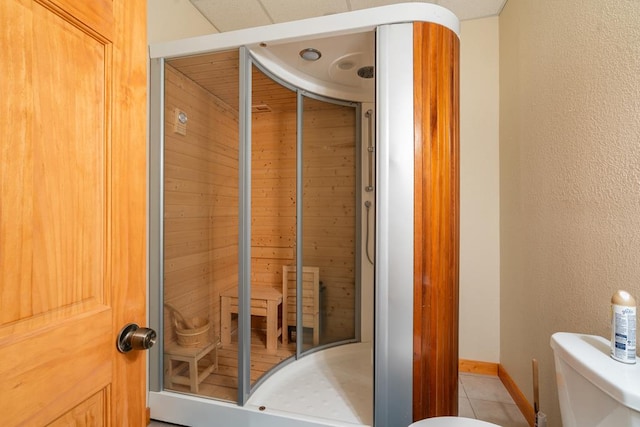 bathroom with wood walls, a shower with door, tile patterned flooring, and toilet