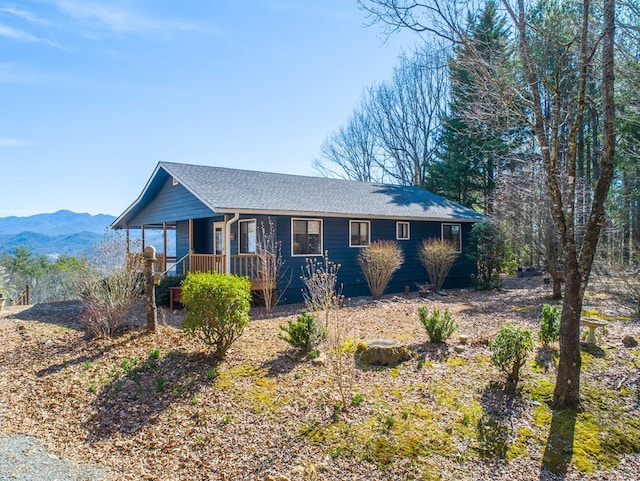 view of front of house with a porch, roof with shingles, and a mountain view