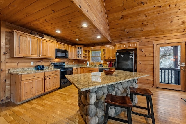 kitchen with light stone countertops, light wood-type flooring, wooden ceiling, a kitchen breakfast bar, and black appliances