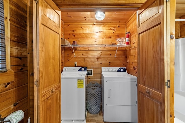 laundry room with separate washer and dryer, wood walls, and laundry area