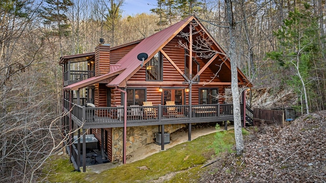 rear view of house with a deck, cooling unit, metal roof, and a chimney