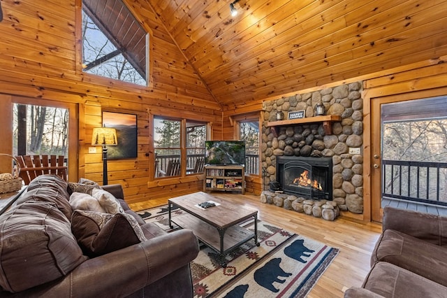 living area featuring high vaulted ceiling, wood finished floors, a stone fireplace, wooden ceiling, and wood walls