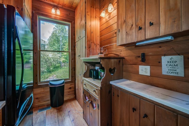 doorway to outside featuring a healthy amount of sunlight, wooden walls, and light wood-type flooring