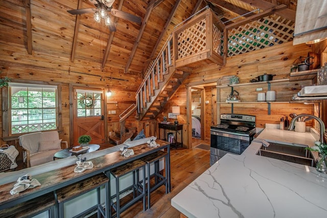 living room with dark hardwood / wood-style floors, wood walls, beamed ceiling, sink, and wood ceiling