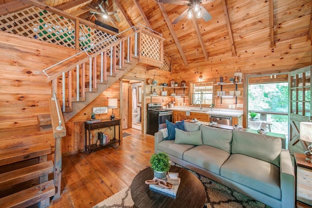 living room with sink, wood walls, wood ceiling, beamed ceiling, and ceiling fan