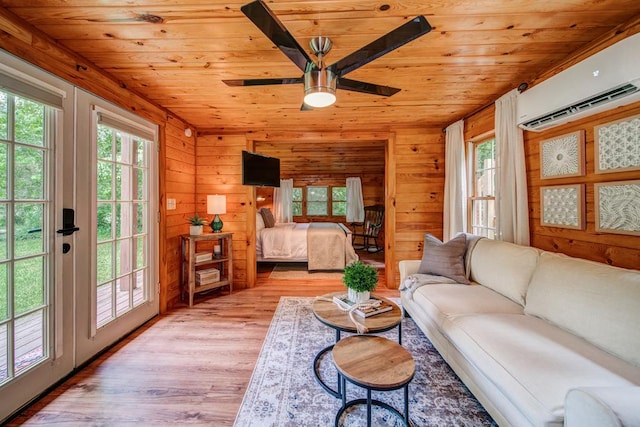 living room featuring light hardwood / wood-style flooring, ceiling fan, wooden walls, wooden ceiling, and an AC wall unit