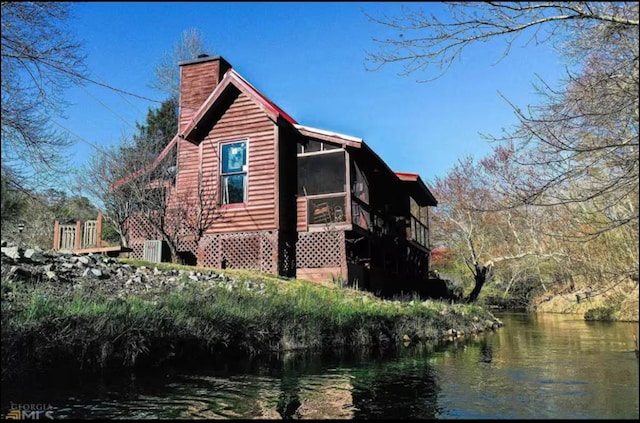 view of property exterior with a water view and a sunroom