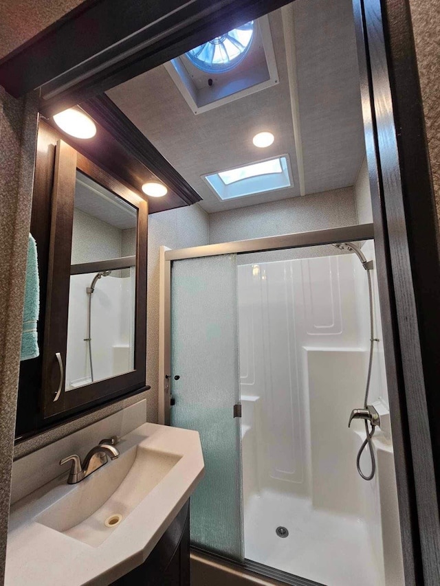 bathroom with a skylight, vanity, and a shower with shower door