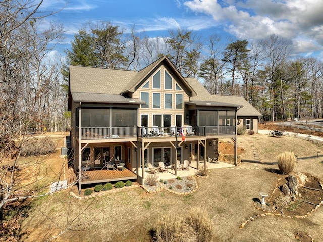 rear view of house with a deck, a patio, and a sunroom