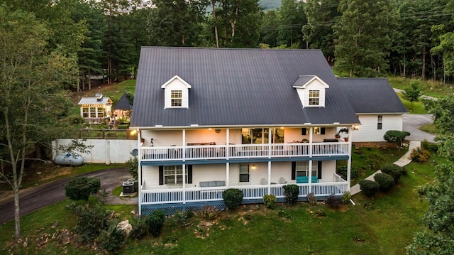 rear view of property with driveway, metal roof, a balcony, and central air condition unit