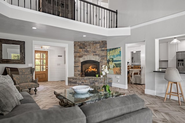 living area with a stone fireplace, a towering ceiling, and baseboards