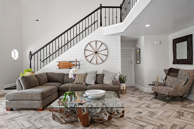 living room with a towering ceiling, baseboards, and stairs