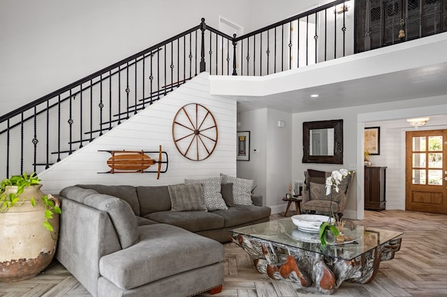 living room featuring a notable chandelier, recessed lighting, a towering ceiling, baseboards, and stairway