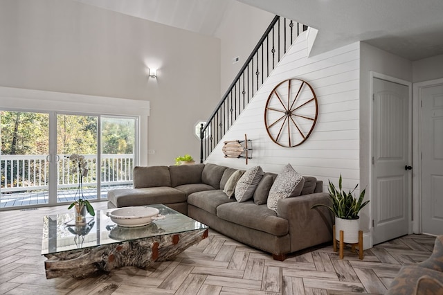 living area with wood walls, a towering ceiling, and stairs