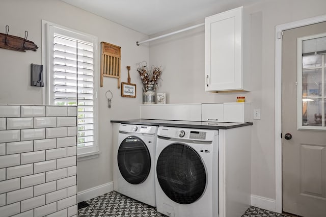 clothes washing area with cabinet space, baseboards, and washer and clothes dryer