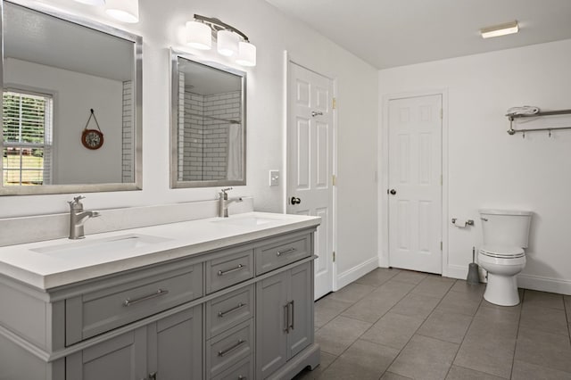 full bath with baseboards, a sink, toilet, and double vanity