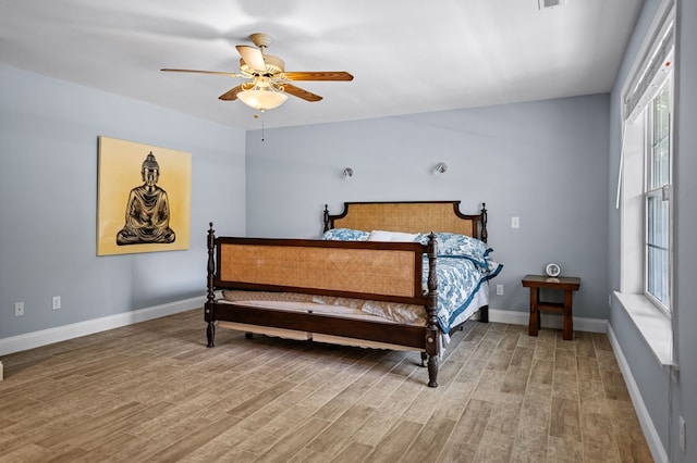 bedroom featuring multiple windows, light wood-style flooring, and baseboards