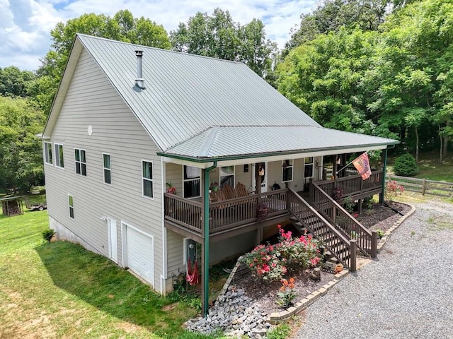 back of house featuring a lawn, covered porch, and a garage