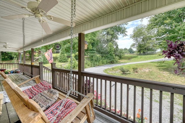 wooden terrace with covered porch, ceiling fan, and a lawn