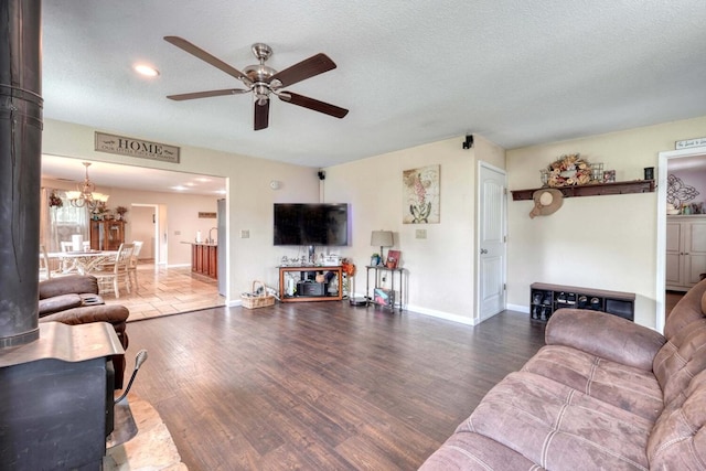 living room with ceiling fan with notable chandelier, wood-type flooring, and a textured ceiling