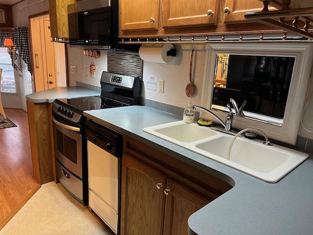 kitchen with dishwashing machine, stainless steel electric range oven, light floors, black microwave, and a sink