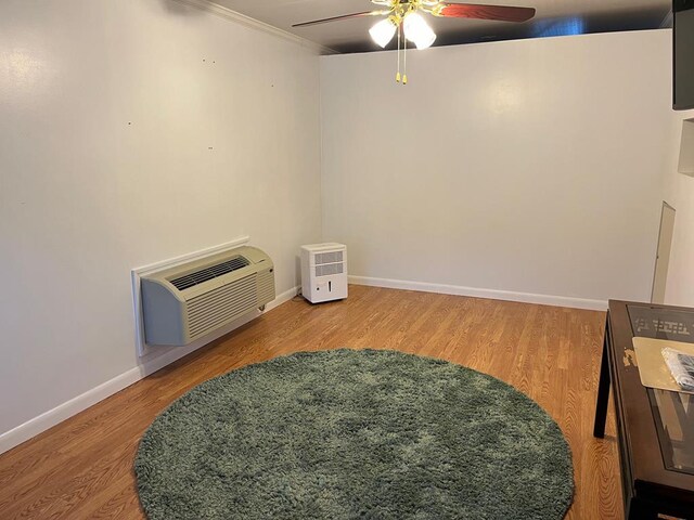 interior space featuring a ceiling fan, wood finished floors, baseboards, and a wall mounted AC