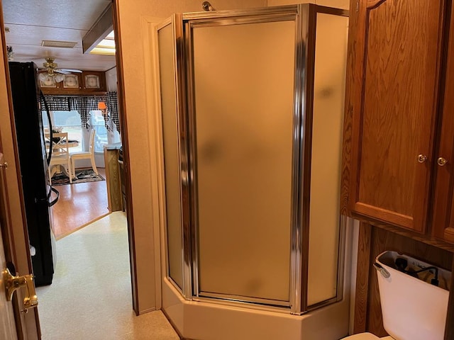 bathroom with a shower with shower door and toilet