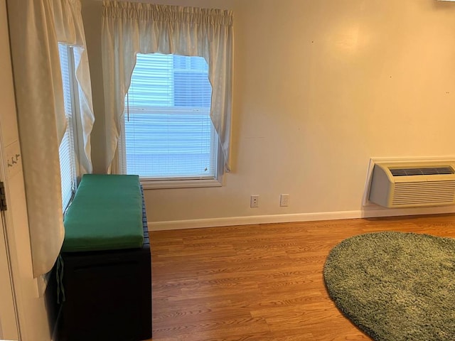 interior space featuring wood finished floors, baseboards, and a wall mounted AC