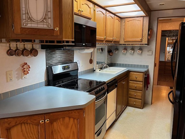 kitchen with dishwasher, electric stove, freestanding refrigerator, light floors, and a sink