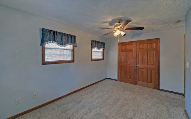 unfurnished bedroom featuring carpet, a textured ceiling, and ceiling fan