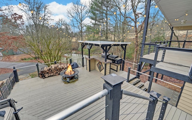 wooden terrace featuring a fire pit, ceiling fan, and area for grilling