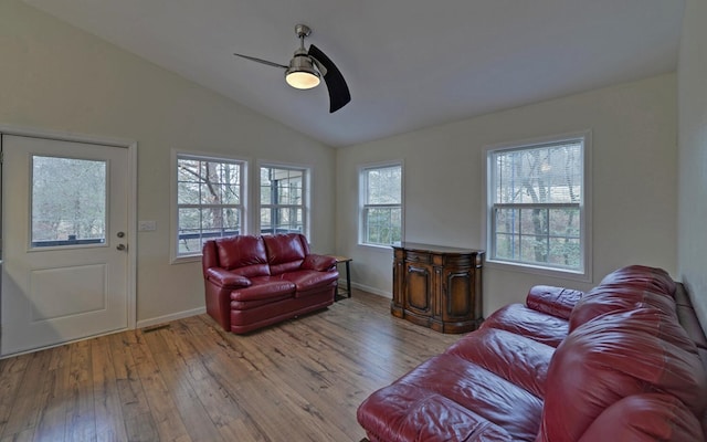 living room featuring ceiling fan, light hardwood / wood-style floors, a wealth of natural light, and vaulted ceiling