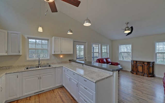 kitchen featuring kitchen peninsula, white cabinetry, hanging light fixtures, and sink