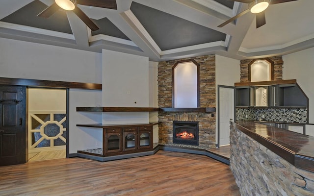 kitchen with ceiling fan, tasteful backsplash, crown molding, wood-type flooring, and a fireplace