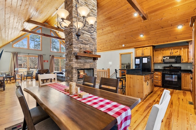 dining room with a stone fireplace, wood ceiling, beam ceiling, and light hardwood / wood-style flooring