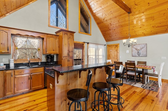 kitchen with sink, a breakfast bar area, hanging light fixtures, light wood-type flooring, and a kitchen island