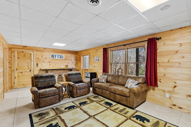 tiled living room featuring a paneled ceiling and wooden walls