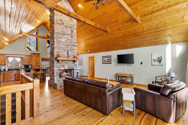 living room featuring wood ceiling, a stone fireplace, and light wood-type flooring