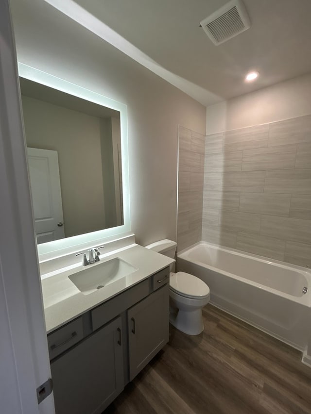 full bathroom featuring wood-type flooring, toilet, tiled shower / bath, and vanity