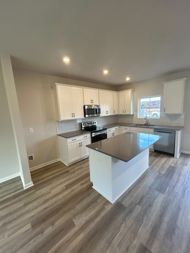 kitchen featuring white cabinets, a center island, dark hardwood / wood-style flooring, and appliances with stainless steel finishes