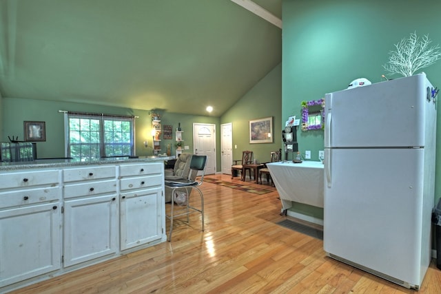 kitchen featuring high vaulted ceiling, white cabinets, light hardwood / wood-style flooring, and white refrigerator